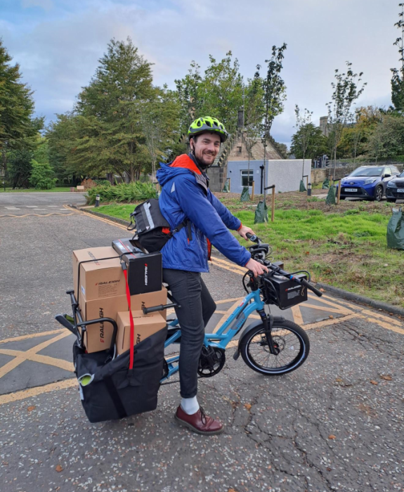 A man riding a tern cargo bike which is carrying several boxes